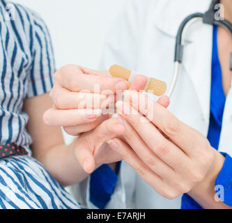 Medico mette bendaggio adesivo sul dito del bambino. Foto Stock