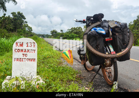 La lettura della fase cardine chilometri da Conakry a Freetown sul finanziato dall'UE di nuova costruzione strada in Sierra Leone Foto Stock