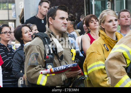 Calgary, Alberta, Canada. Undicesimo Sep, 2014. Un incendio calgarian fighter tiene a New York City Fire Fighters bandiera mentre riflette sul tredicesimo anniversario del World Trade Center di attentati terroristici. Credito: Baden Roth/ZUMA filo/Alamy Live News Foto Stock