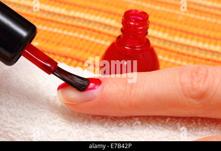 Rosso smalto applicato al chiodo di mano, manicure processo, la cura delle unghie Foto Stock
