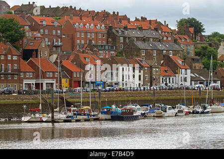 Rosso affollate case di mattoni e blocchi di appartamenti sulla ripida collina accanto al porto / marina con barche in inglese città costiera di Whitby, Foto Stock