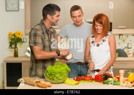 Vista frontale il gruppo di amici in piedi in cucina, preparare un pasto Foto Stock