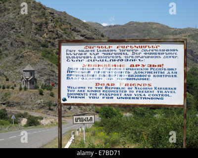 Un segno in armeno, russo e inglese educatamente informa di un passaporto e visto controlla quando entrando nella Repubblica di Nagorno-Karabakh alla strada da Goris a Stepanakert, Armenia, 26 giugno 2014. La Repubblica di Nagorno-Karabakh è indipendente de facto ma non riconosciuto a livello internazionale stato contestato tra Armenia e Azerbaigian. La regione senza sbocchi sul mare nel Caucaso del Sud è abitata da armeni. Foto: Jens Kalaene - Nessun servizio di filo- Foto Stock