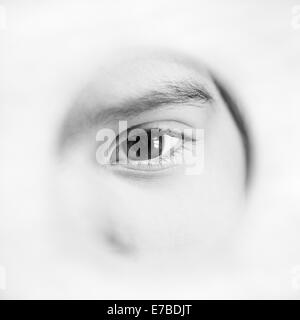 Occhio di grave bambina spiata attraverso il foro Foto Stock