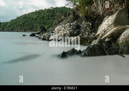 Una lunga esposizione delle onde che lambiscono contro le rocce in Hawksnest Bay Foto Stock
