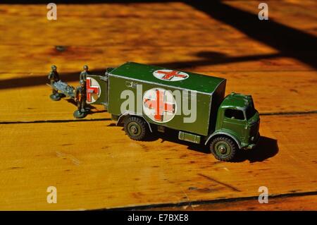 Un esercito giocattolo ambulanza sorge sul pavimento in pannelli di legno con toy soldier barellieri caricamento di un uomo ferito a bordo Foto Stock