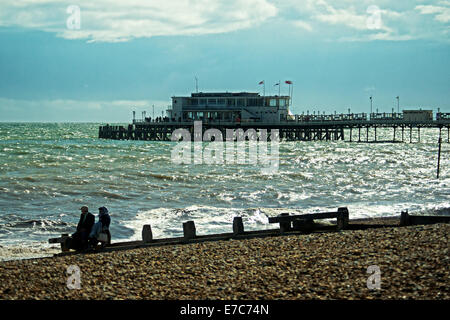 Un paio di sedersi sul mare difese a Worthing, con Worthing Pier in background. Foto Stock