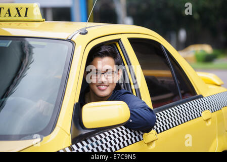 Ritratto di felice chinese taxi driver in giallo auto sorridente e guardando la fotocamera Foto Stock