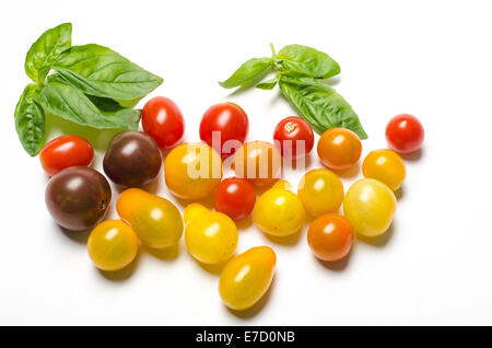 Tutto il cimelio di famiglia di pomodori ciliegini e le foglie di basilico su sfondo bianco Foto Stock