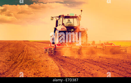 L'agricoltore nel trattore preparazione della terra per la semina Foto Stock