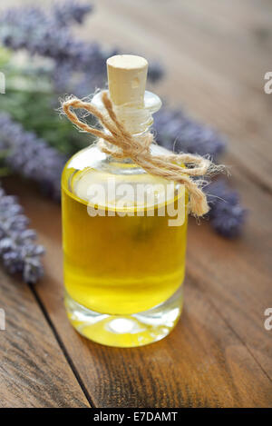 Essenziale di olio di lavanda con fiori freschi su sfondo di legno closeup Foto Stock