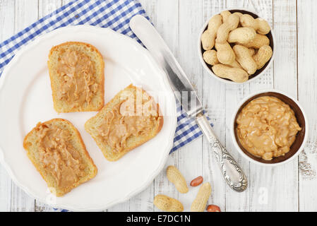 Sandwich al burro di arachidi sulla piastra con i dadi su sfondo di legno. Vista dall'alto. Foto Stock