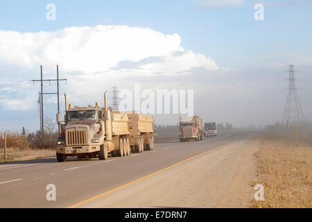 Autocarri pesanti su strada polverosa, Fort McMurray, Alberta, Canada Foto Stock