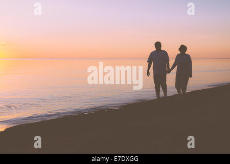 Coppia senior camminando lungo la spiaggia Foto Stock