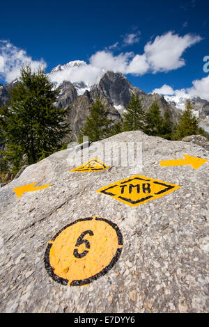 Guardando verso il Mont Blanc da sopra la Val Veny, Italia, con una parete di roccia segnata con il Tour du Mont Blanc a lunga distanza sentiero. Foto Stock