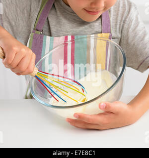 Ragazzo terrina di burro e zucchero usando un miscelatore, facendo una torta, 8 anni Foto Stock