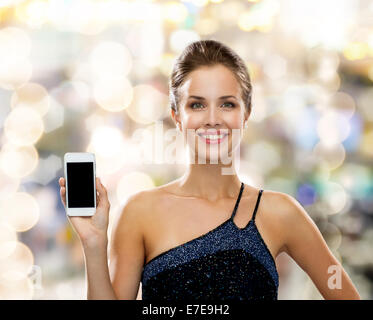 Donna sorridente in abito da sera con lo smartphone Foto Stock