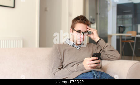 Giovane uomo la lettura di un testo sul suo smartphone. Foto Stock