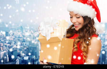 Donna sorridente in santa helper hat con confezione regalo Foto Stock