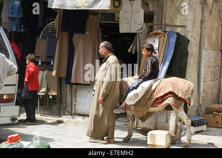 I bambini su un asino con un uomo vecchio nel bazar di Aleppo, Siria Foto Stock