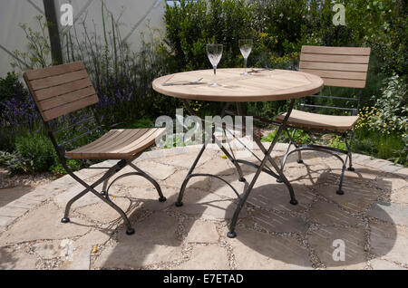 Piccolo giardino circolare giardino patio circolare in pietra Purbeck pavimentata con tavolo in legno e sedie UK Foto Stock