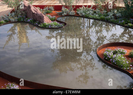 Giardino - Essenza di Australia - Vista del laghetto in giardino piscina circondata da Brachyscome blu - Designer - Jim Fogart Foto Stock