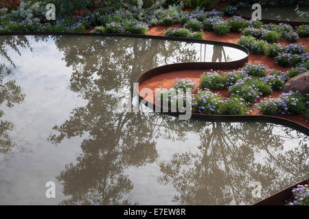 Giardino - Essenza di Australia - Vista del laghetto in giardino piscina circondata da Brachyscome blu - Designer - Jim Foto Stock