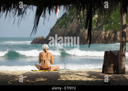 Una giovane donna si rilassa sulla spiaggia vicino al mare tartaruga nidificazione terreni a Maruata, Michoacan, Messico. Foto Stock