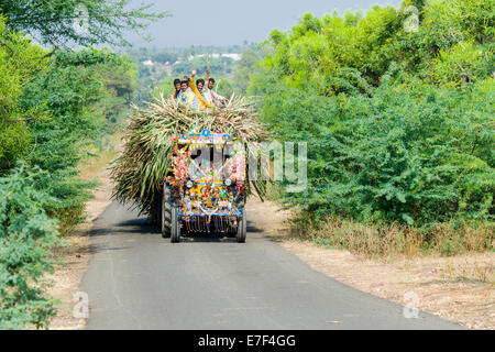 Un trattore è il trasporto di canna da zucchero, alcuni agricoltori in cima, agitando, Aihole, Karnataka, India Foto Stock