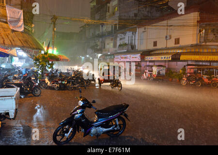 Scena di strada con una strada allagata durante forti piogge monsoniche di notte, il centro città di Phnom Penh, Cambogia Foto Stock