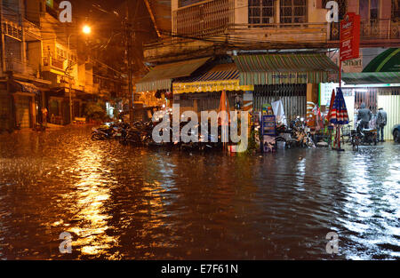 Scena di strada con una strada allagata durante forti piogge monsoniche di notte, il centro città di Phnom Penh, Cambogia Foto Stock