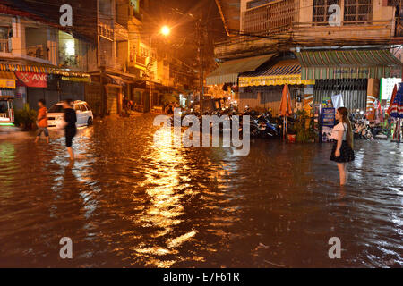 Scena di strada con una strada allagata durante forti piogge monsoniche di notte, il centro città di Phnom Penh, Cambogia Foto Stock