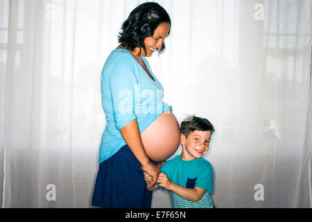 Ragazzo ascoltando la madre del ventre in stato di gravidanza Foto Stock