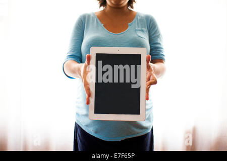 Incinta donna ispanica azienda computer tablet Foto Stock