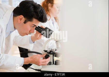 Scienziato usando microscopio in laboratorio Foto Stock