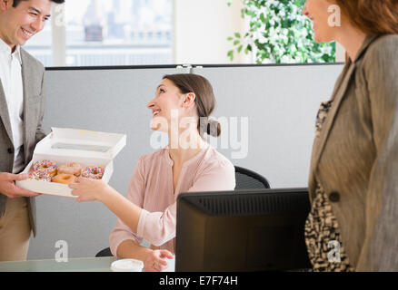 La gente di affari avente le ciambelle in office Foto Stock