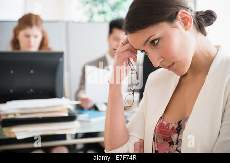 Imprenditrice di graffiare la sua testa in office Foto Stock