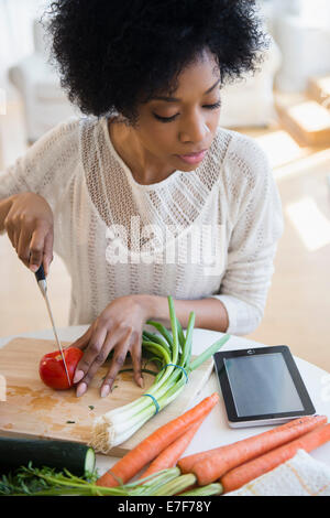 African American donna utilizzando computer tablet per cucinare Foto Stock