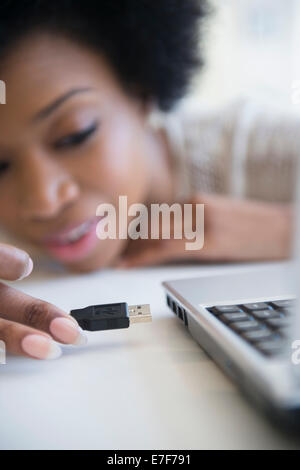 African American donna collegando il cavo USB nel computer portatile Foto Stock