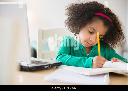 African American Girl facendo compiti a casa con il computer portatile Foto Stock