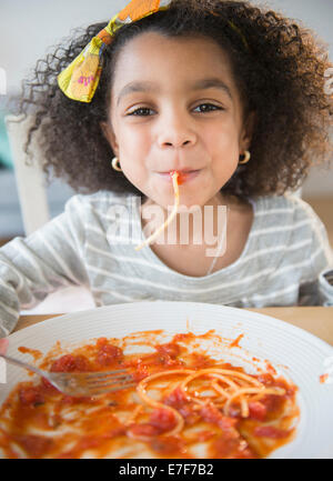 African American Girl mangiare spaghetti a tavola Foto Stock