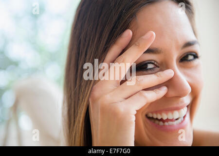 Close up della donna del peering attraverso le dita Foto Stock