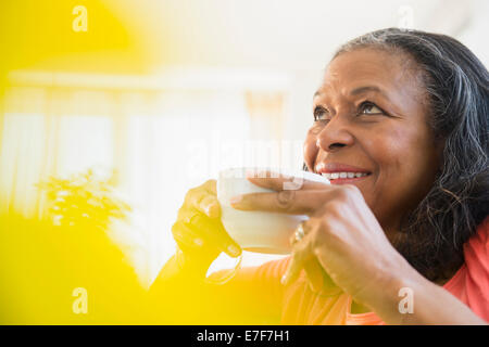 Razza mista donna bere tazza di caffè Foto Stock