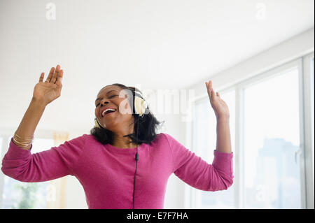 Razza mista donna ascoltando le cuffie in salotto Foto Stock