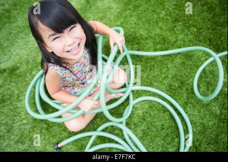 Ragazza filippina giocando con il tubo flessibile nel cortile posteriore Foto Stock