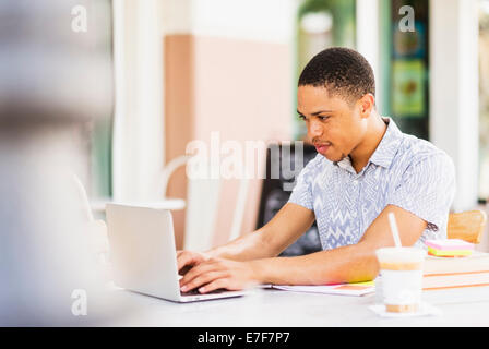 African American uomo utilizzando computer portatile presso cafè sul marciapiede Foto Stock