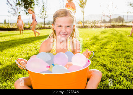 Ragazza caucasica giocando con palloncini di acqua nel cortile posteriore Foto Stock