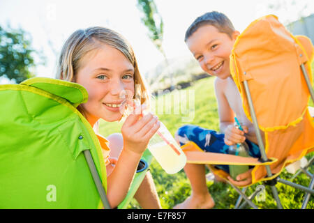 Bambini caucasici bere soda in cortile Foto Stock