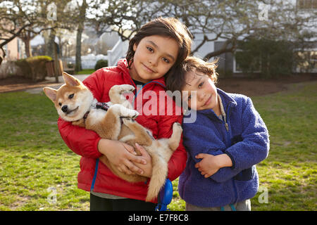 Razza mista fratelli holding puppy in cortile Foto Stock