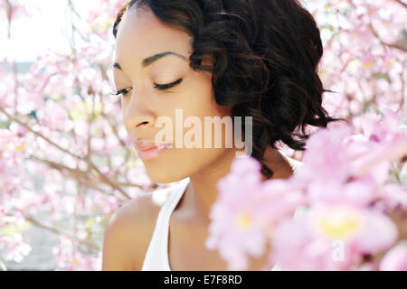 African American woman standing dalla struttura ad albero di fioritura Foto Stock